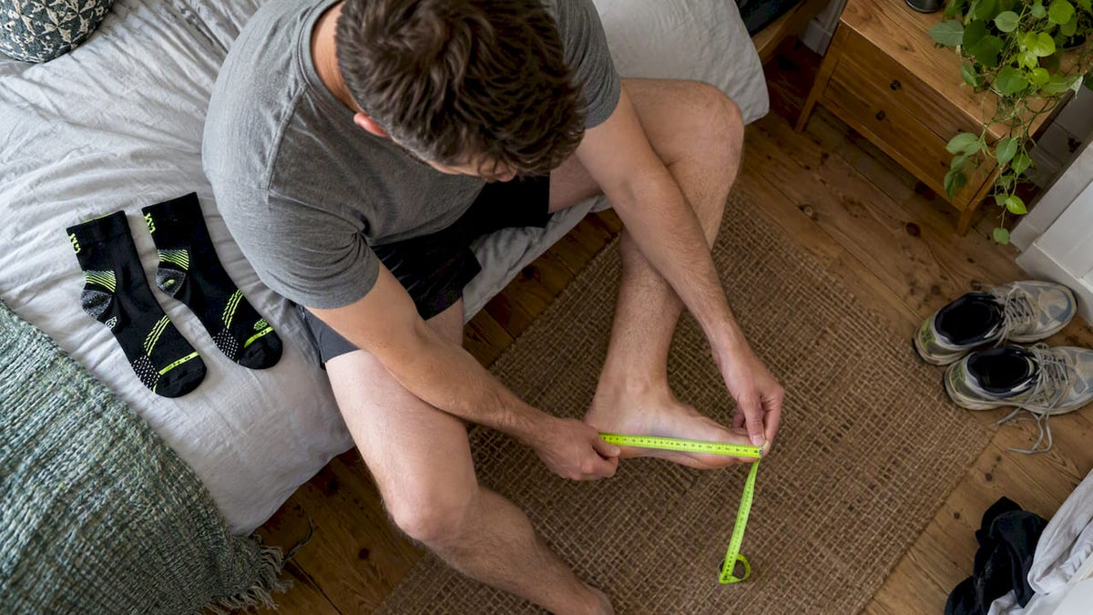 Runner measuring foot beside STRYQ running socks