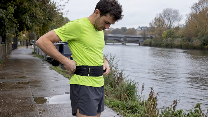 Runner readjusting a STRYQ belt on a towpath