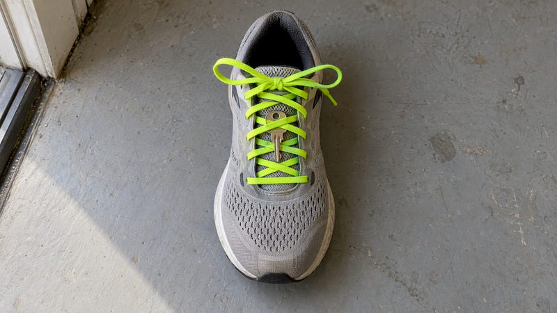 Key secured beneath crossed running shoe laces
