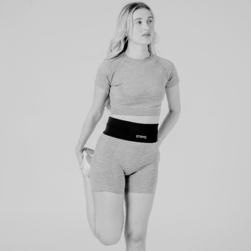Woman wearing a STRYQ running belt on a road run